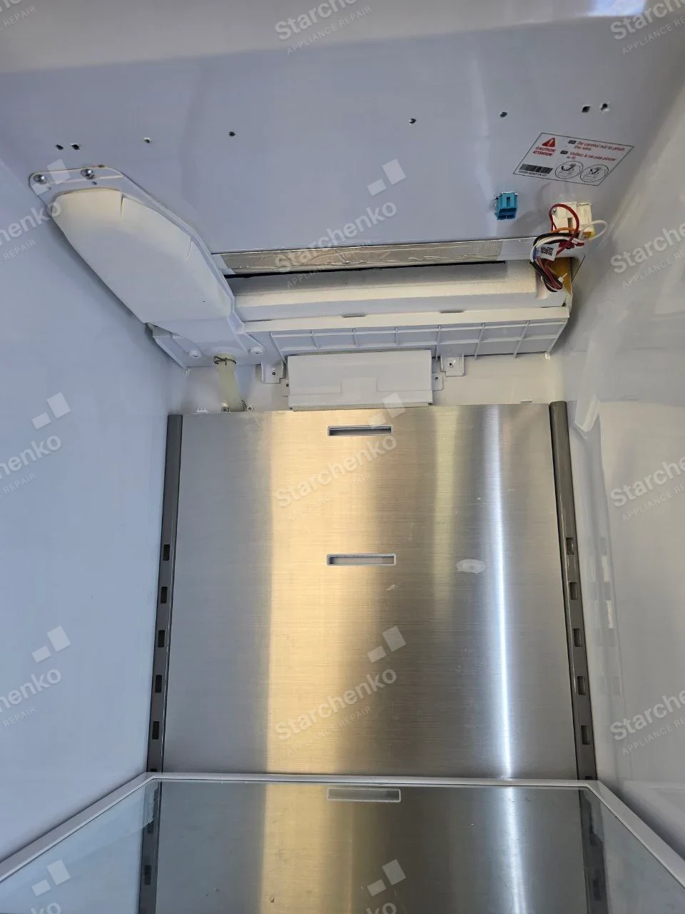 Kenmore repair: Interior of empty refrigerator compartment with rear cooling cover removed, exposing wiring and air duct.