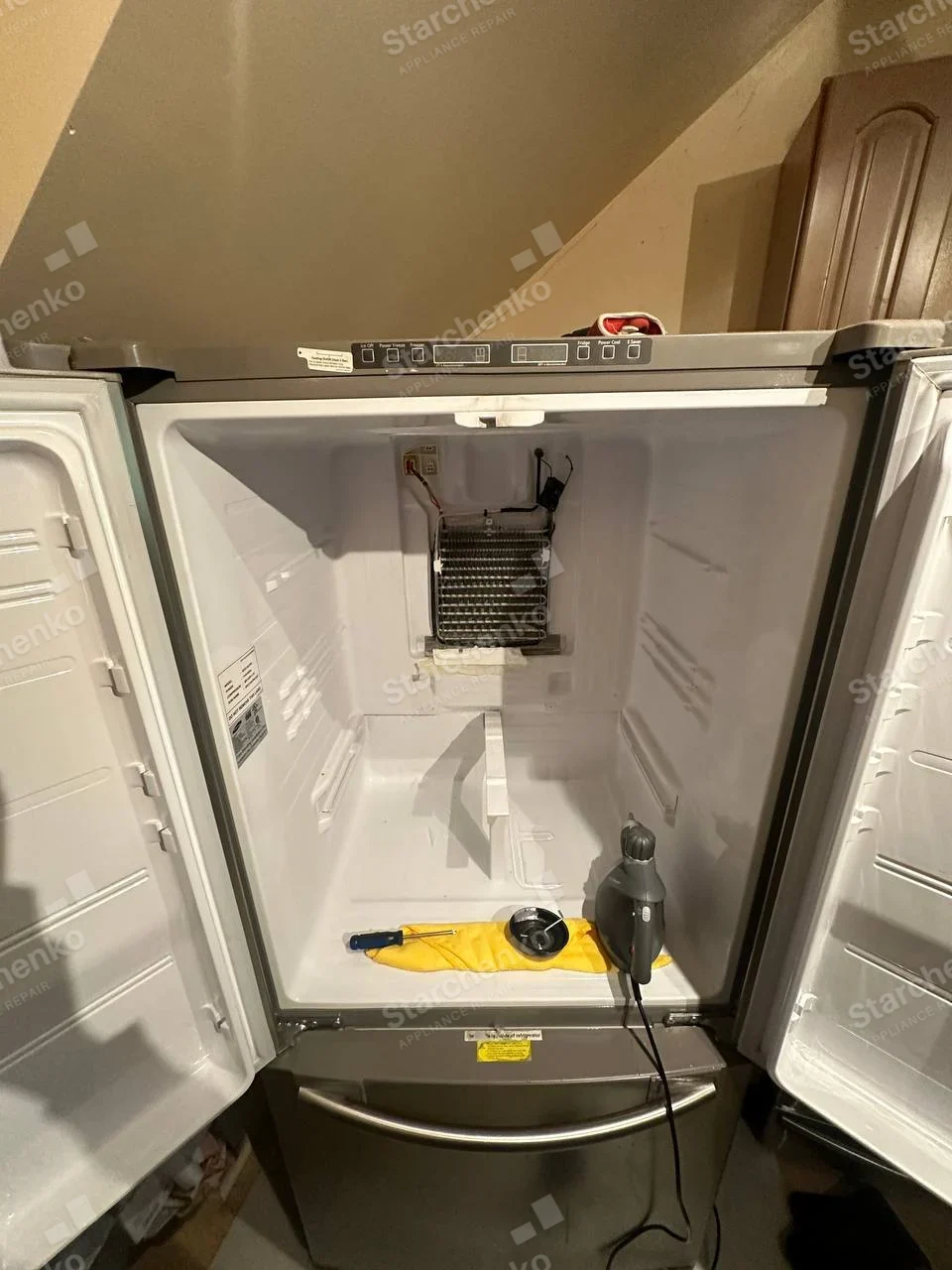 Kenmore repair: French-door refrigerator compartment empty with rear evaporator cover removed, exposing cooling coil, freezer drawer below.