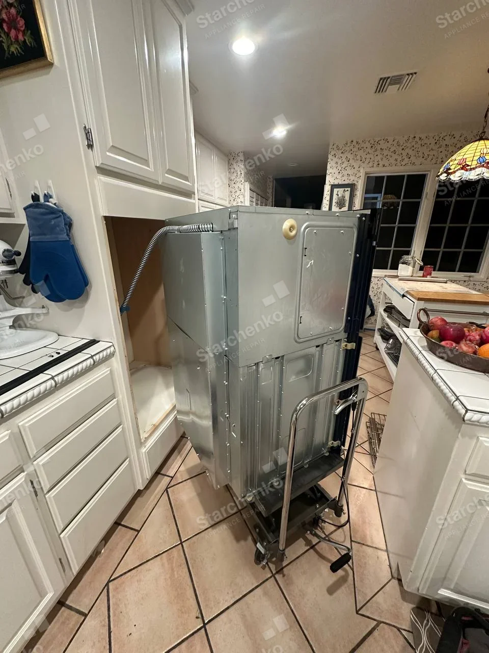 Electrolux repair: Rear of double wall oven removed from cabinet on service lift, two stacked cavity backs and power conduit visible.
