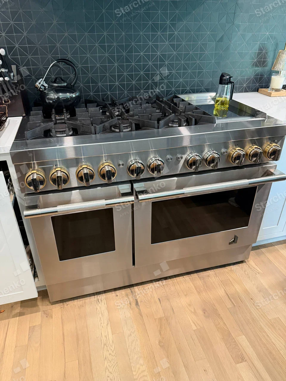 GE Monogram repair: Large dual-oven gas range with numerous burner controls and griddle, but no readable brand on the appliance front.