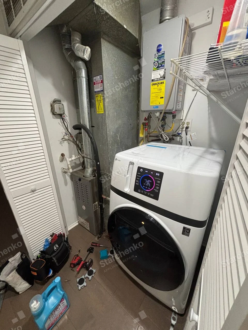 Haier logo on upper-left front of white front-load laundry machine, service tools and detached parts nearby.