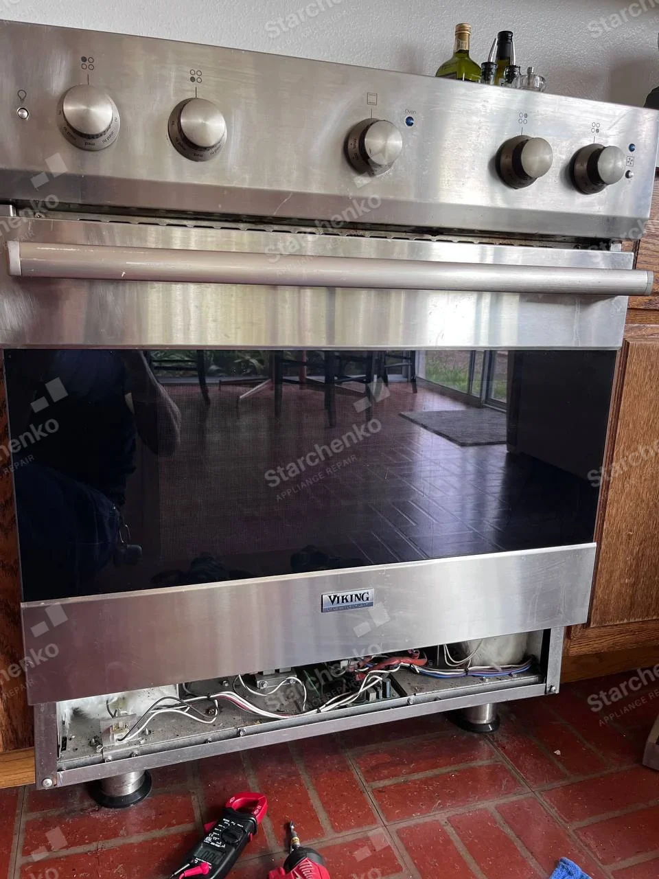 Viking stainless range with lower service panel removed, exposing wiring below oven.