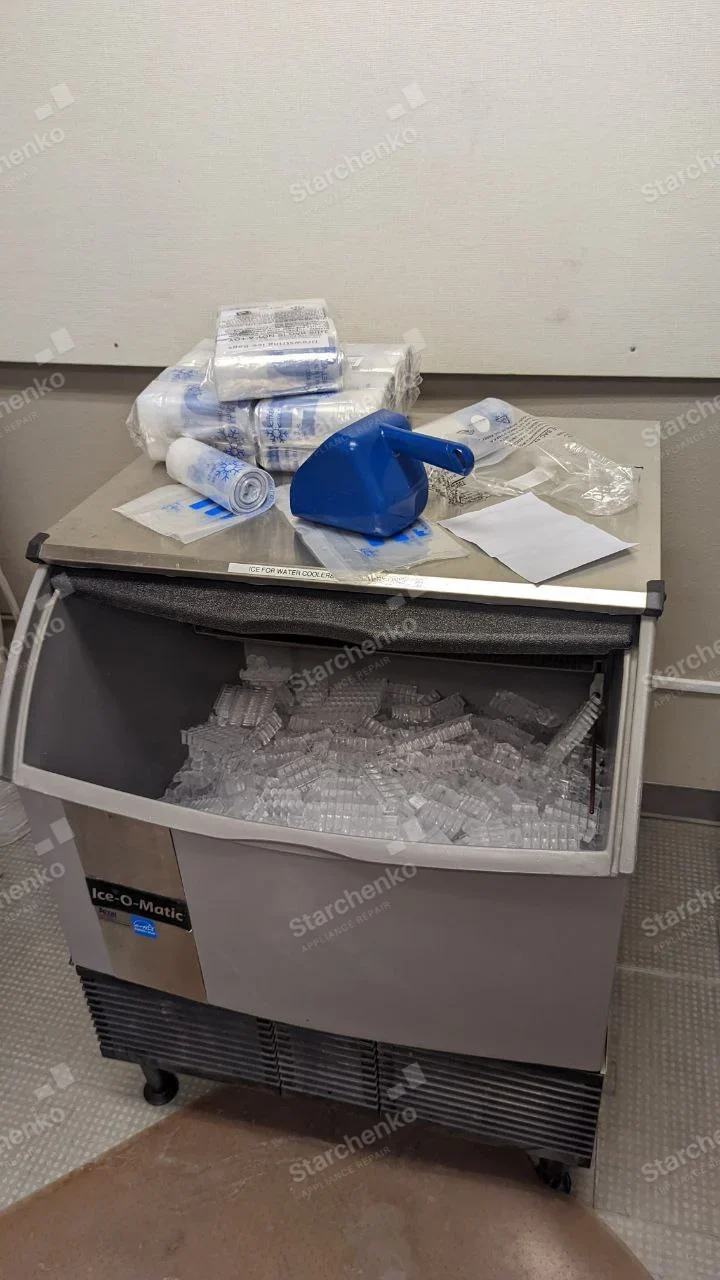 Ice-O-Matic stainless ice machine with front bin open and filled with cubed ice.