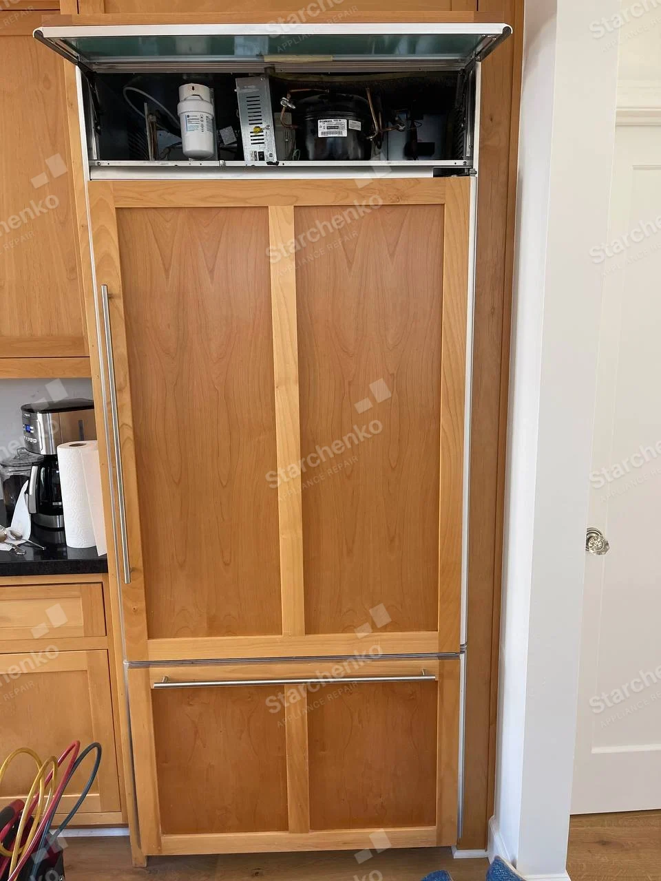 Wood-paneled built-in Viking refrigerator with lower freezer drawer and top machinery hatch open.