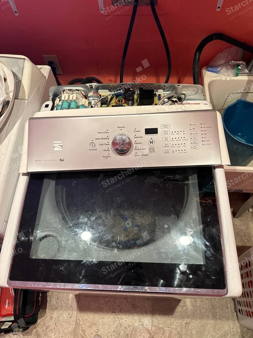 Kenmore top-load washer with control console opened and inlet valves exposed.