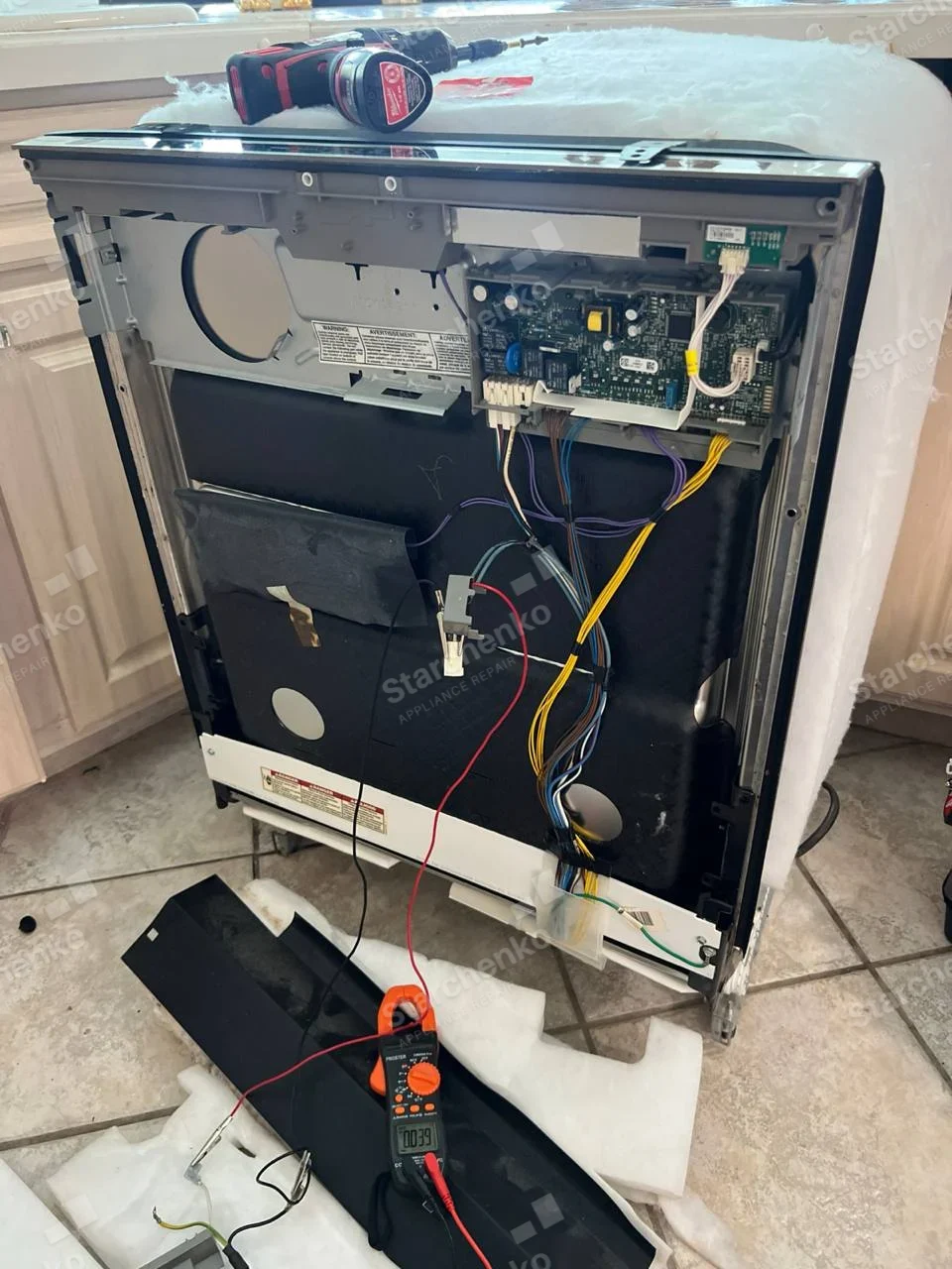LG repair: Dishwasher removed from cabinet and back insulation lifted, exposing electronic control board and wiring.