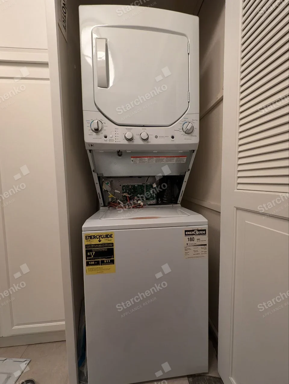 GE repair: Upper dryer of compact laundry tower with lower front access panel removed showing circuitry, lower washer is separate.