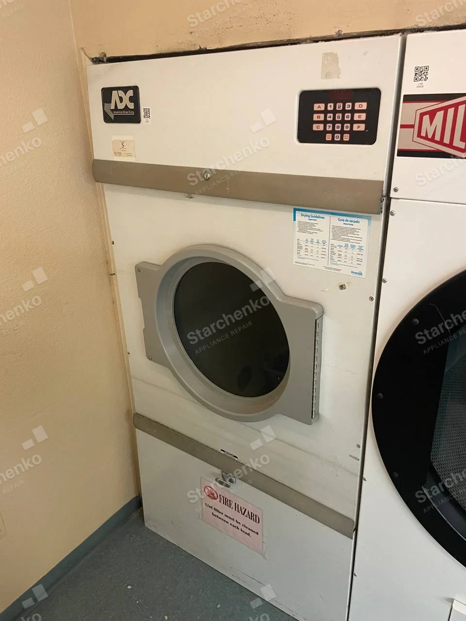 American Dryer (ADC) repair: ADC American Dryer Corp logo on upper-left dryer panel, front-loading commercial dryer.