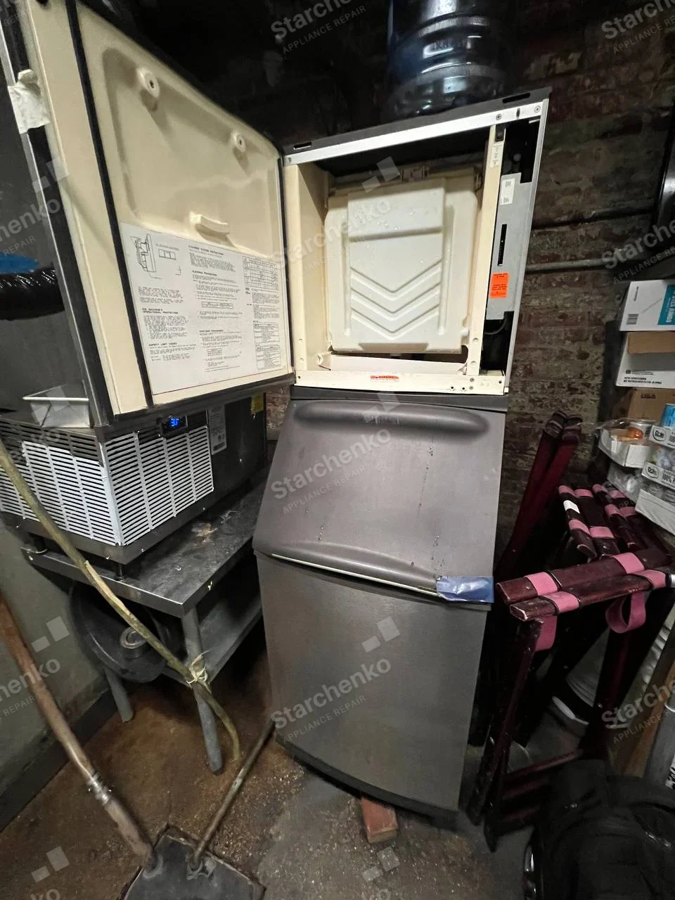 Manitowoc repair: Commercial modular ice machine with upper service door open above an ice storage bin.
