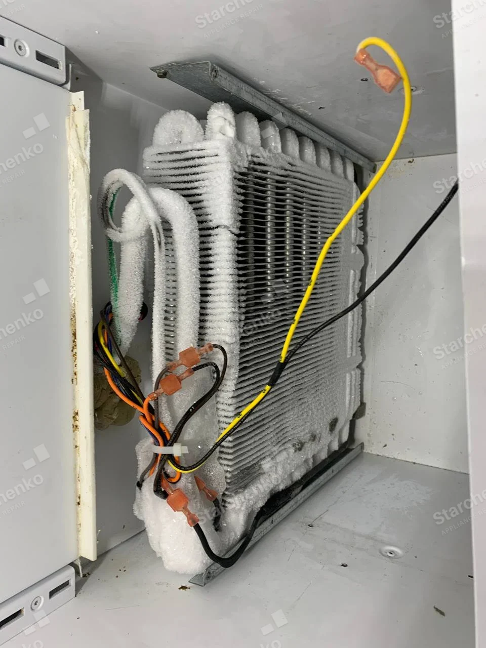 Kenmore repair: Close-up of refrigerator evaporator coil coated in frost with exposed wiring.