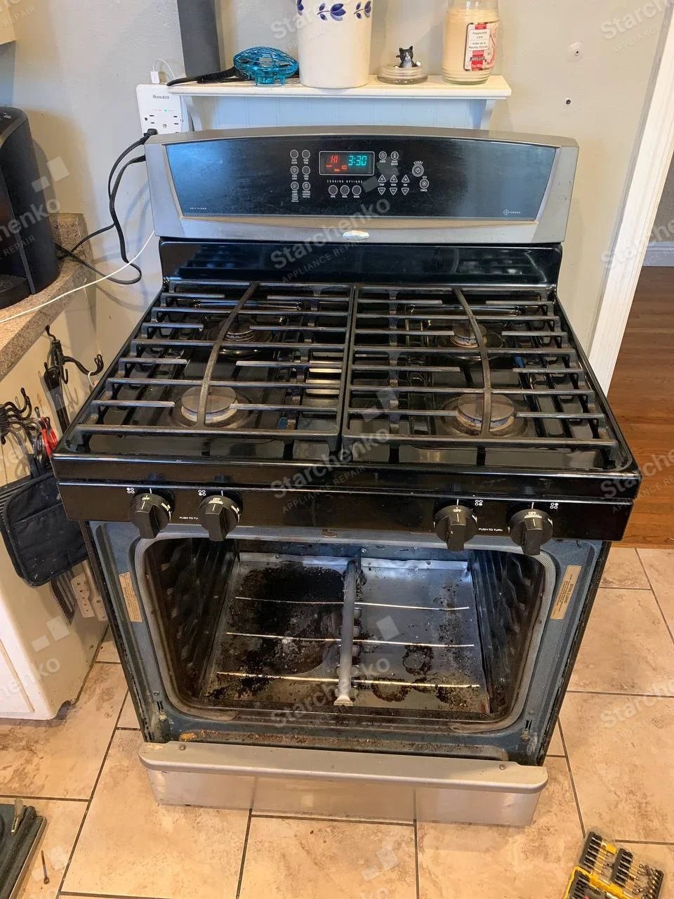 Whirlpool gas range with four burners and removed oven door exposing oven cavity.
