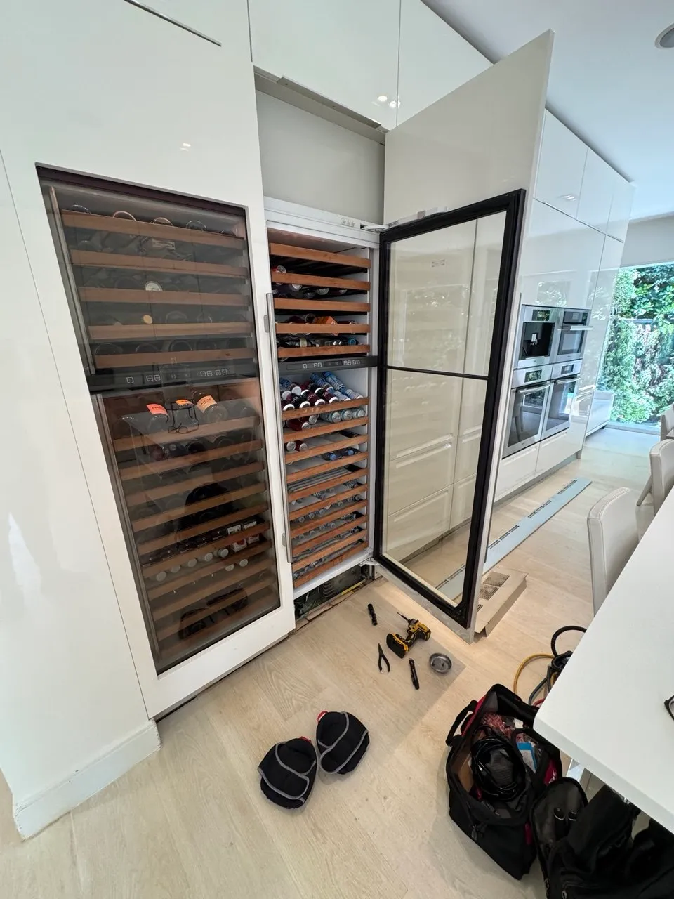 Tall glass-door wine cellar with wooden racks in a kitchen