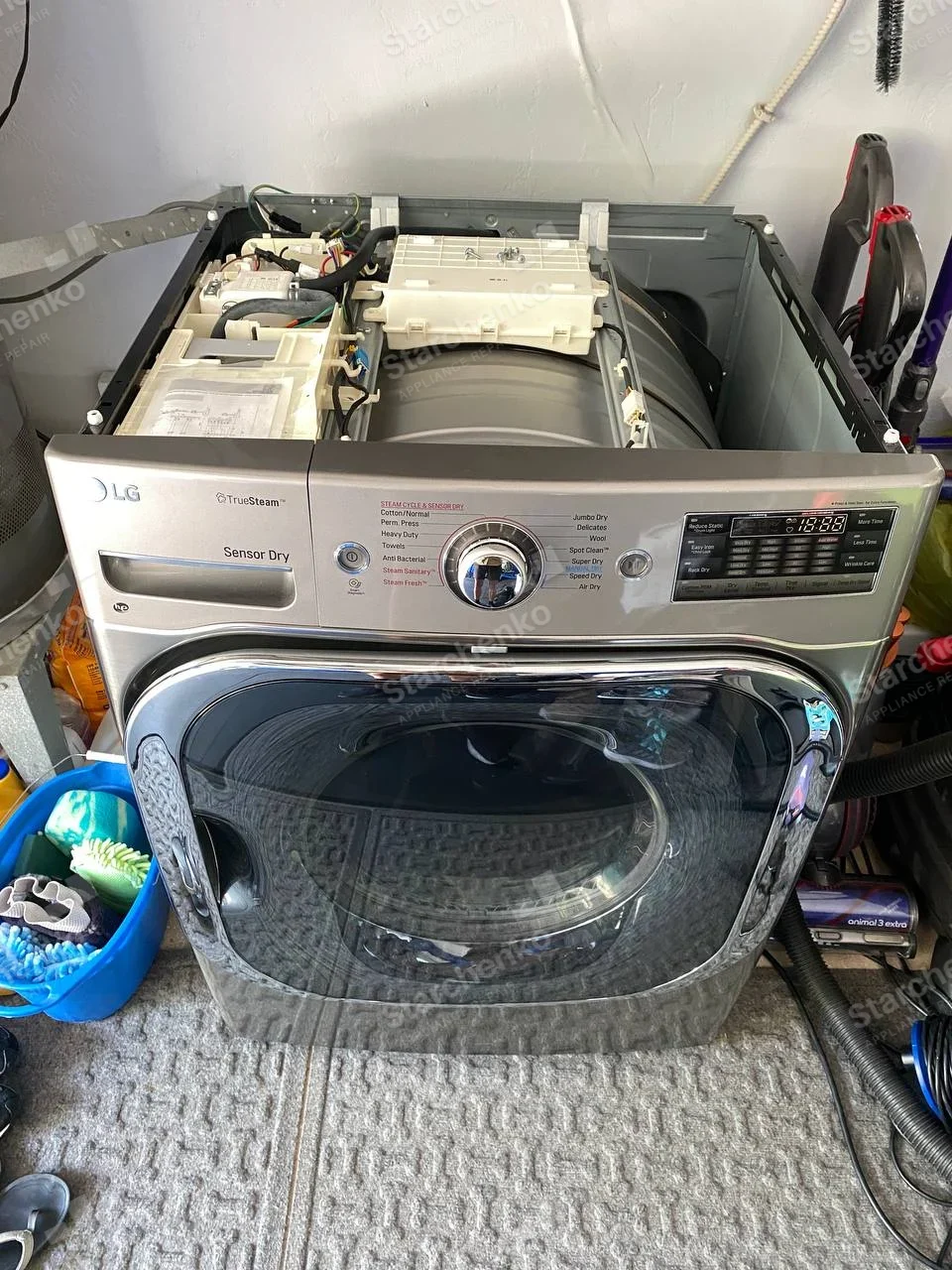 LG front-load dryer with top removed, drum and upper electrical assemblies exposed.