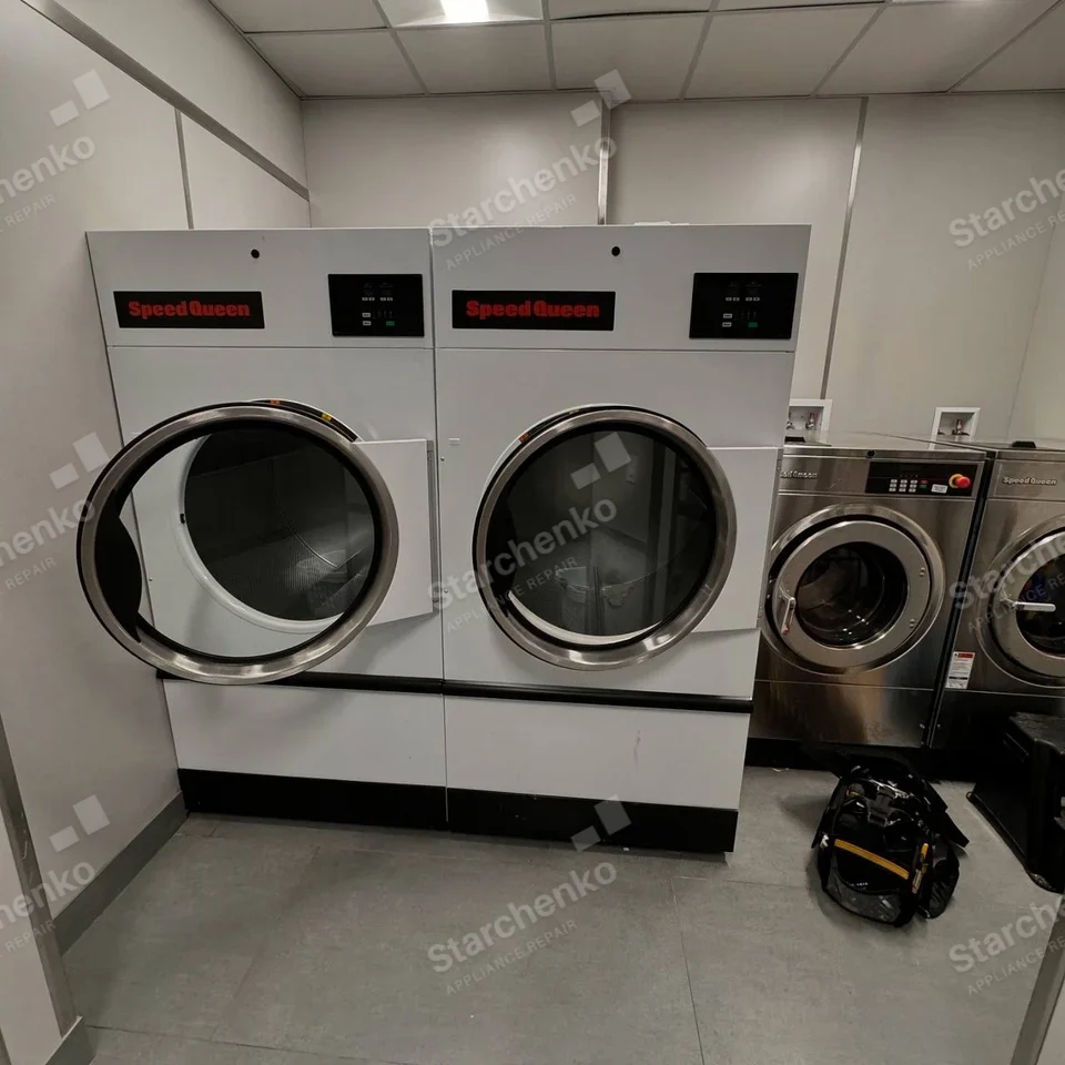 Pair of large white Speed Queen commercial dryers with circular front doors.