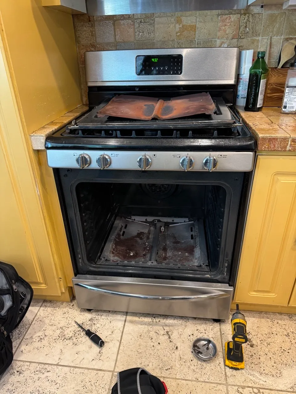 Gas range with the oven door open and the oven floor panel removed to reach the burner