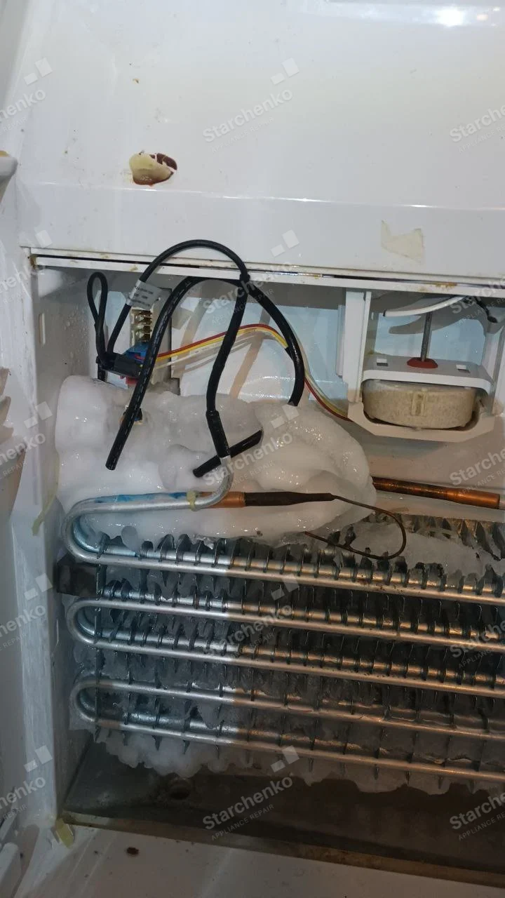 Kenmore repair: Exposed refrigerator evaporator coil and fan with heavy frost and ice buildup.
