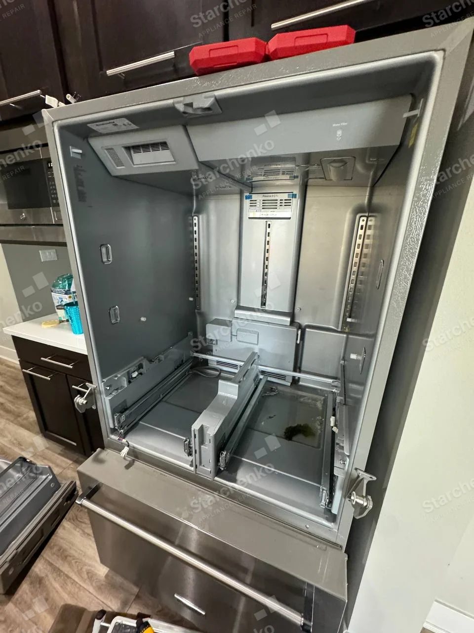 Maytag repair: Open refrigerator compartment with shelves/door trim removed, exposed rear evaporator cover and lower freezer drawer visible.