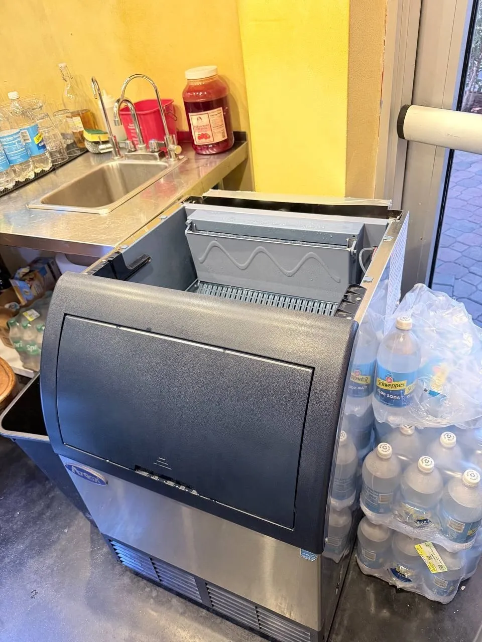 Atosa commercial ice machine in a bar with its top cover removed and evaporator plate exposed