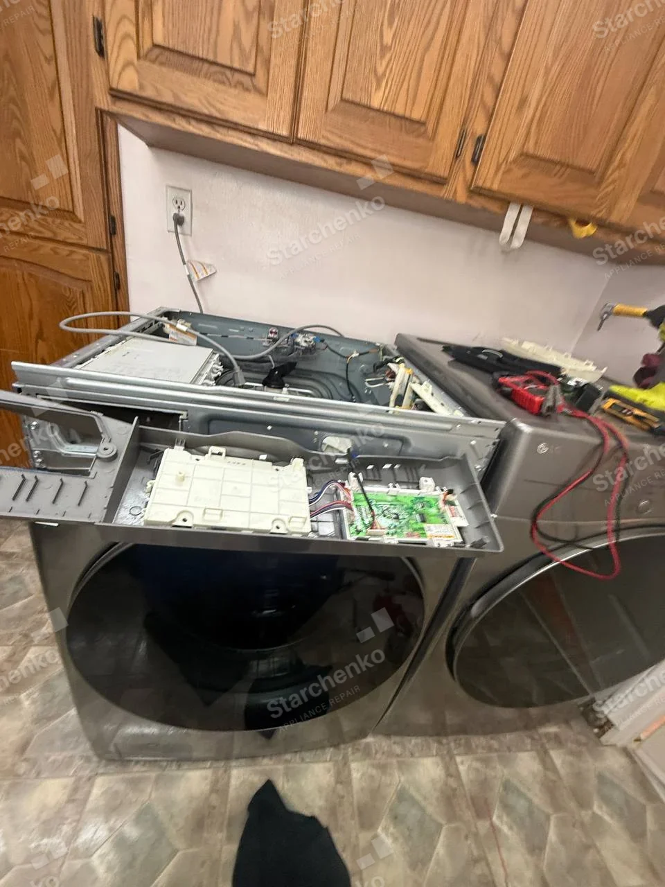 Frigidaire repair: Left front-load laundry appliance has its top/control tray removed with boards exposed.