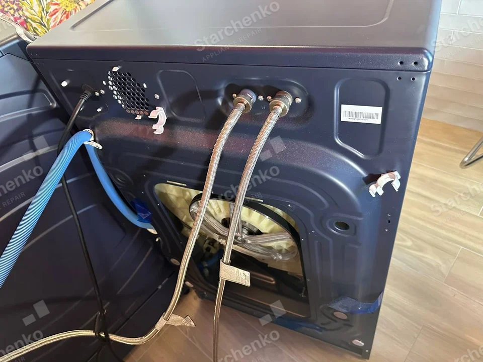 Frigidaire repair: Rear of washer with inlet hoses, drain and exposed motor through removed lower rear panel.