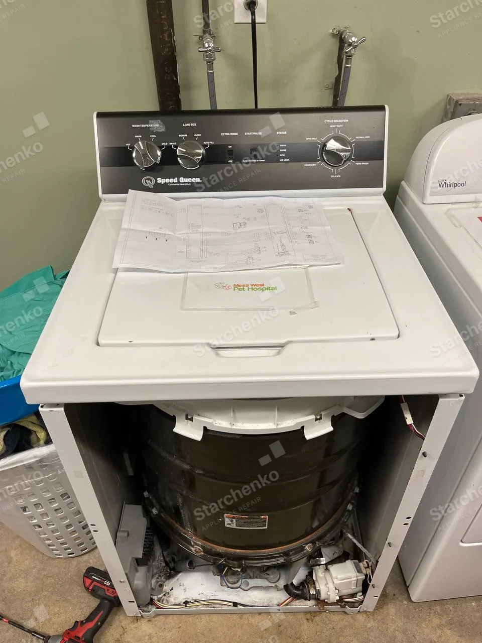 Speed Queen top-load washer with front panel removed, exposing tub and lower pump.