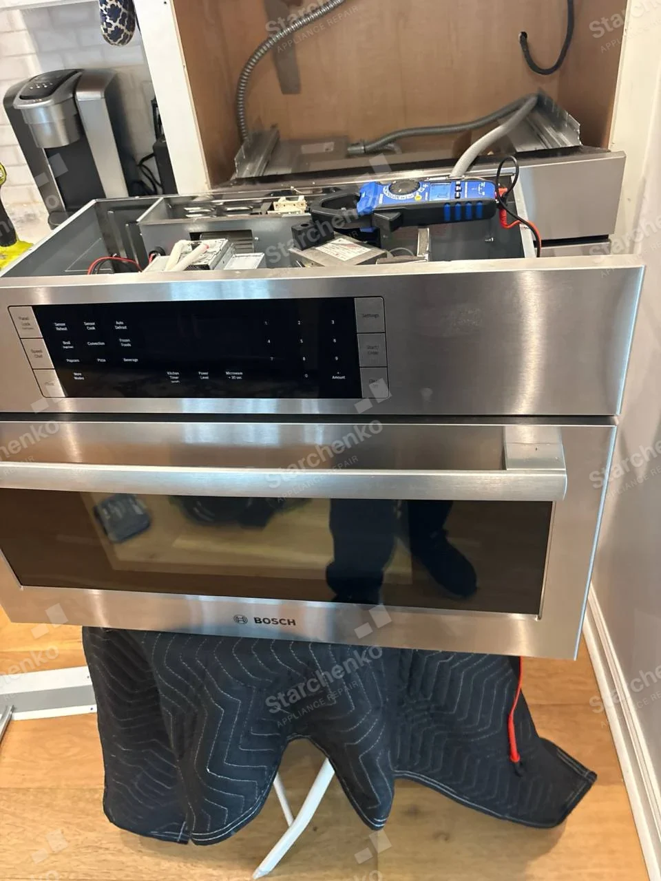 BOSCH wordmark on lower front frame of the pulled-out built-in microwave, top electrical compartment exposed.