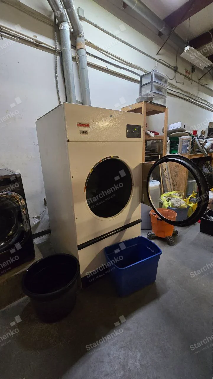 CISSELL badge on upper-left fascia of vented industrial dryer, large circular door open.