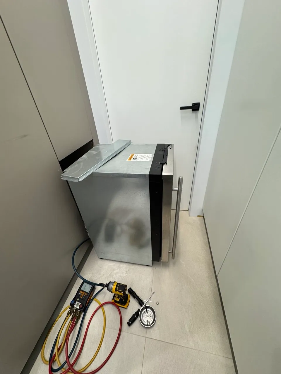 Undercounter ice maker pulled out with manifold gauges on the floor