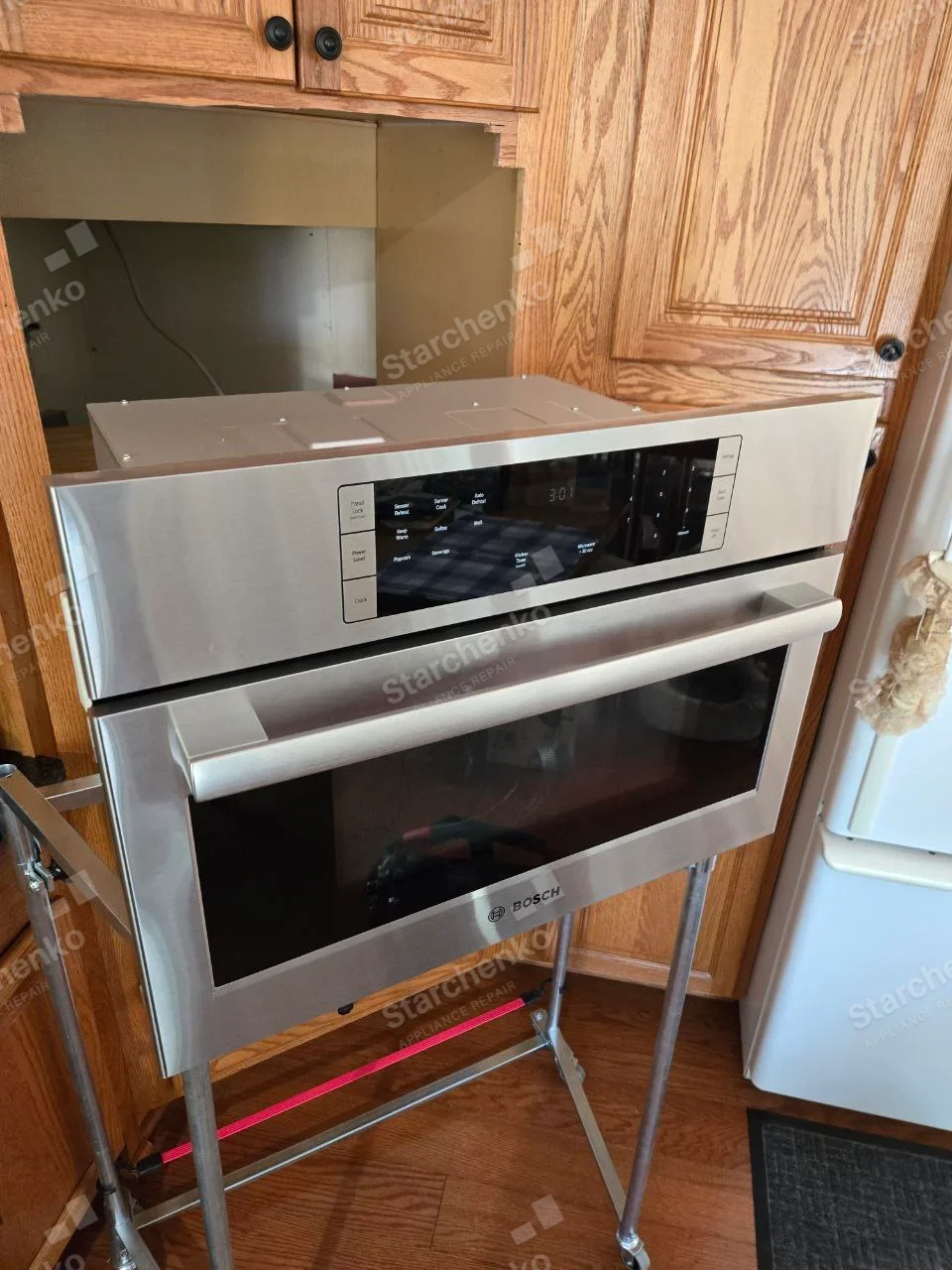 Bosch stainless built-in microwave pulled from cabinet onto a rolling service stand.