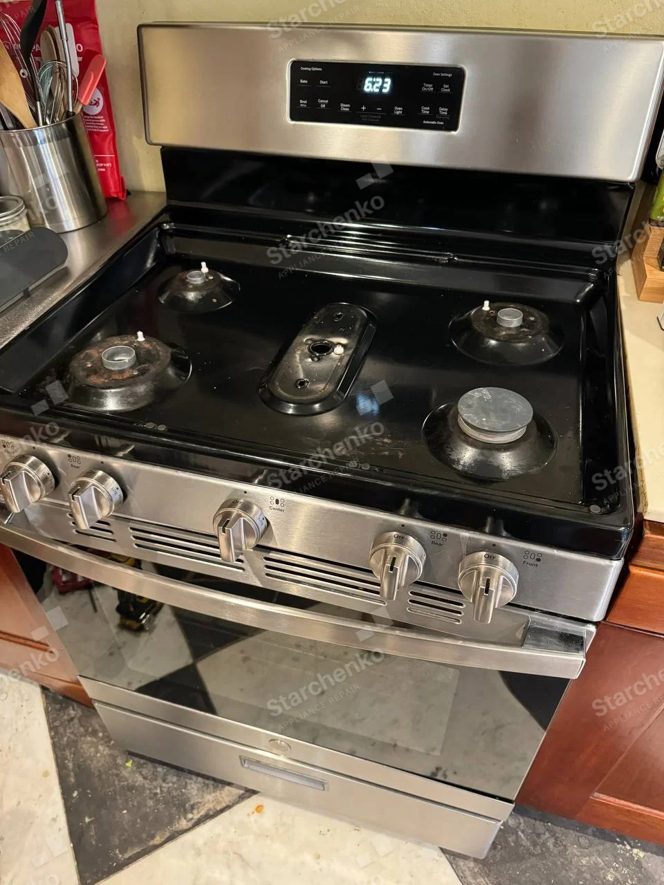 Amana repair: Four gas burners and central oblong burner with caps/grates removed, oven below.