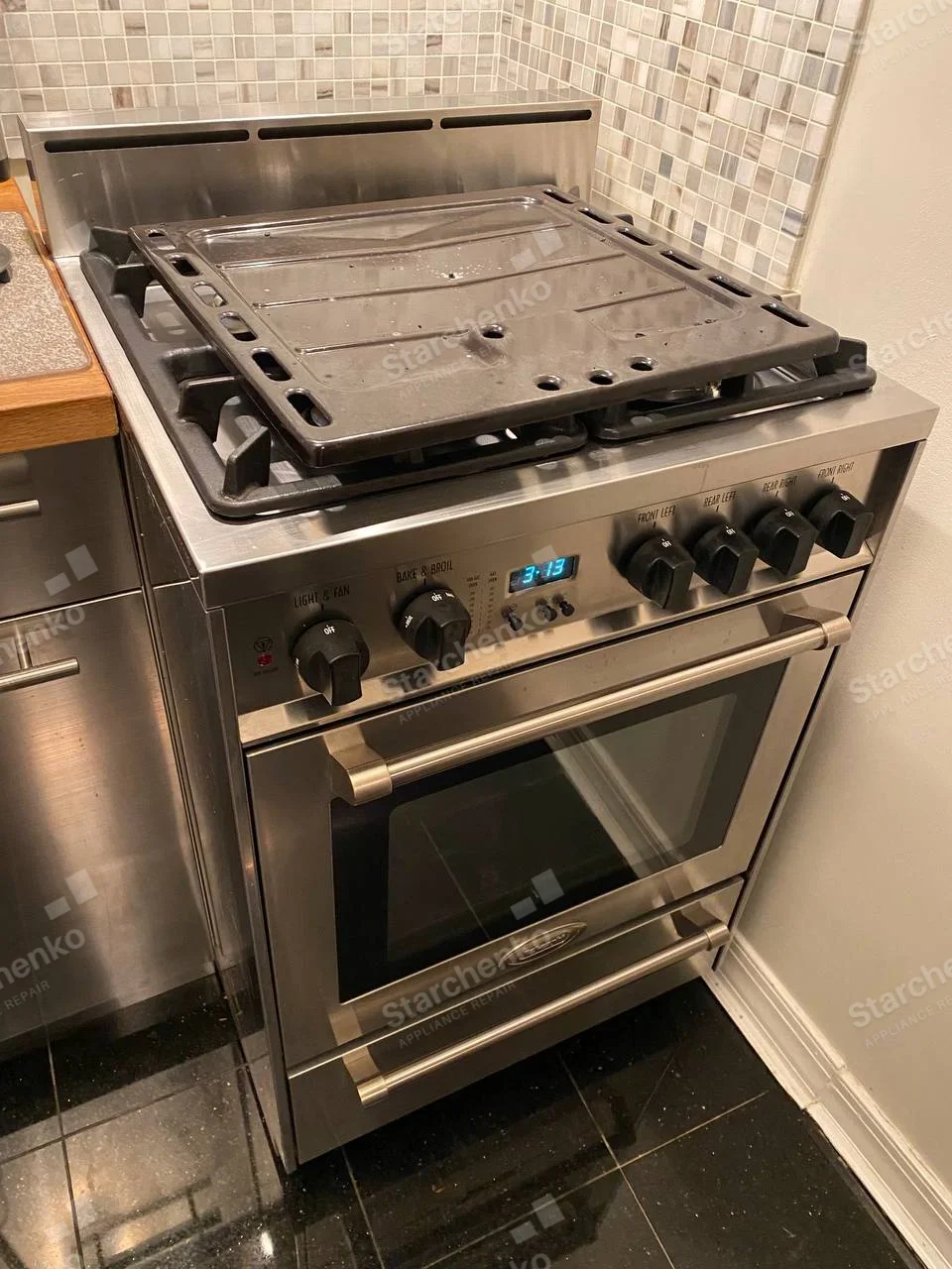 Amana repair: Stainless gas range with metal plate resting on exposed cooktop and front controls visible.