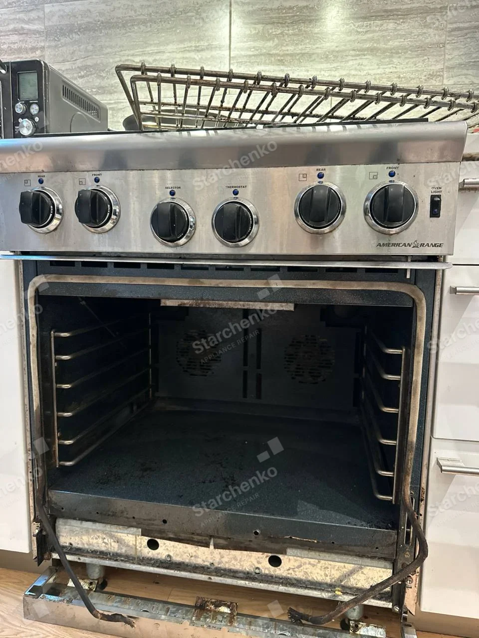 AMERICAN RANGE lettering on right control fascia of gas range, oven door removed and cavity exposed.