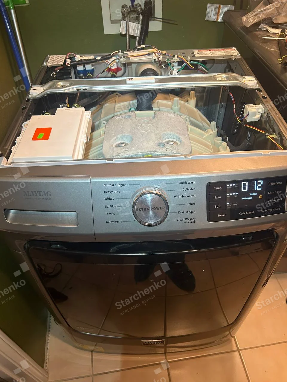 Maytag repair: Front-load washer with top panel removed, showing tub, counterweight, and control wiring.