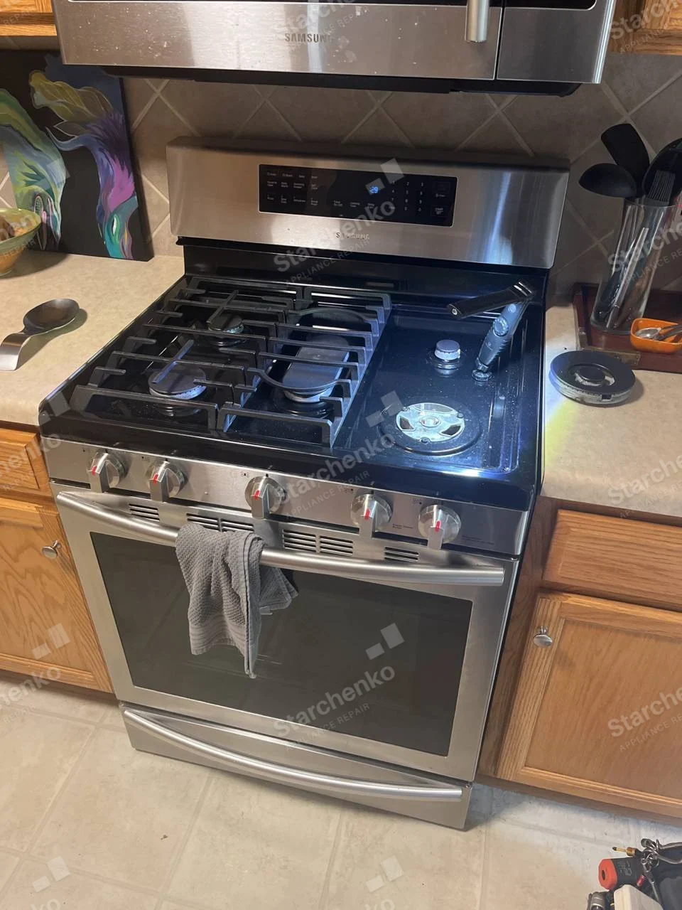 Samsung gas range with one front burner cap removed and ignition area illuminated.