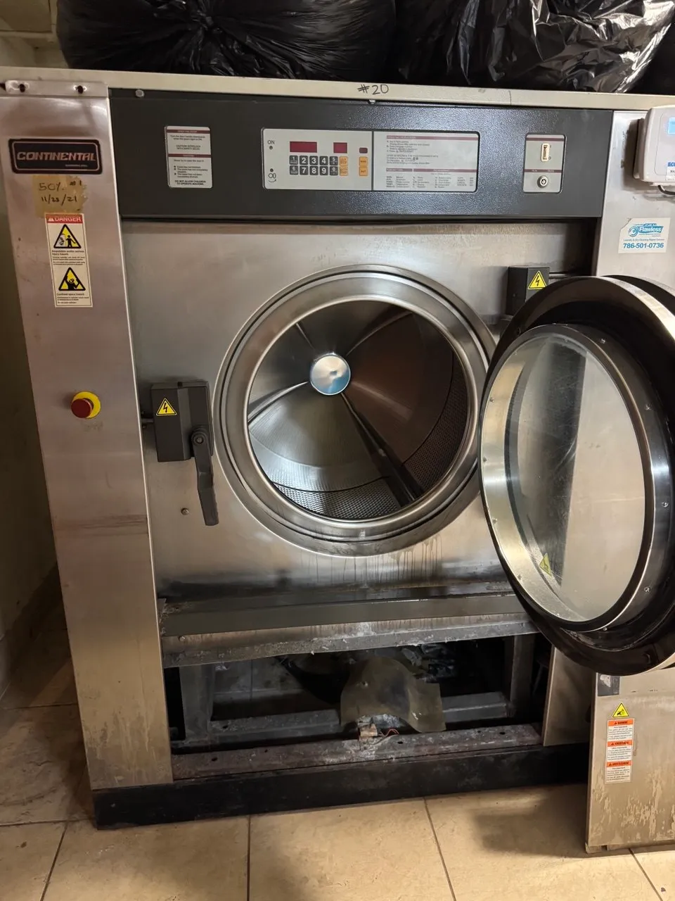 Continental commercial washer with its front panel removed in a shared laundry room