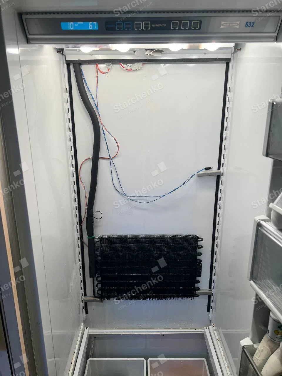 Sub-Zero refrigerator interior with shelves removed, evaporator coil and wiring exposed on rear wall.