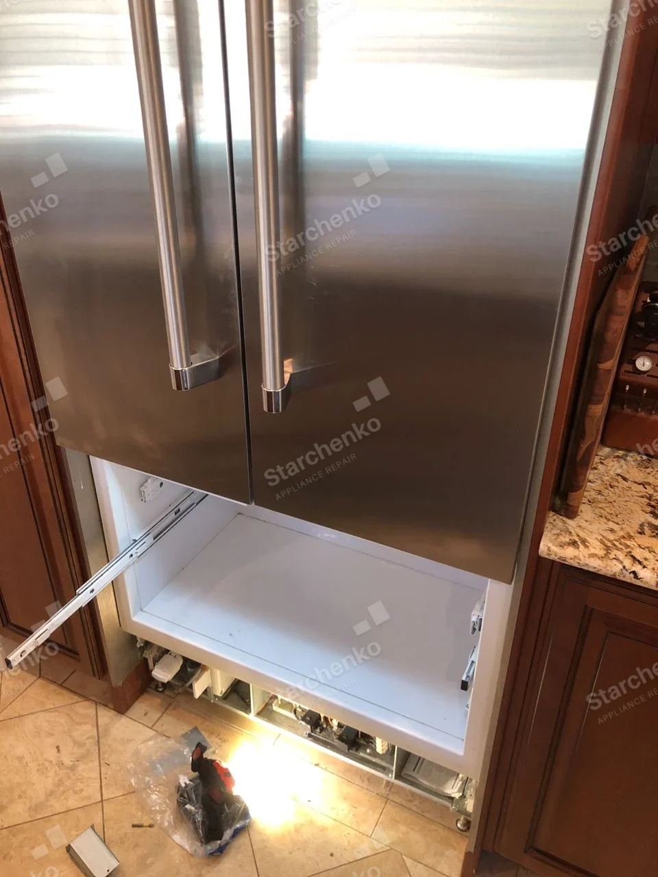 Maytag repair: Stainless French-door refrigerator with bottom freezer drawer removed and slide rails exposed.