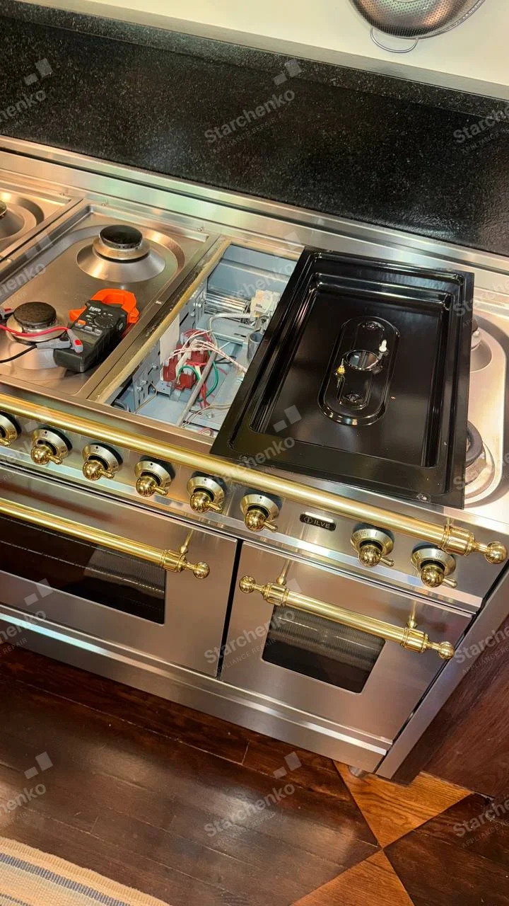 ILVE badge above right oven door on wide gas range with gold controls, central cooktop module removed exposing wiring.