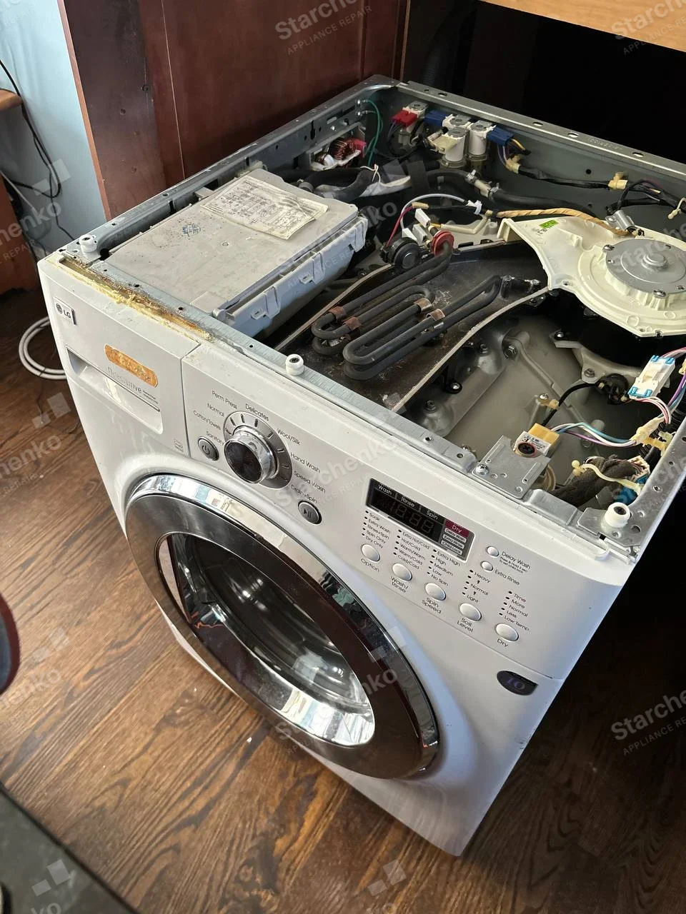 LG front-load washer-dryer with the top panel removed, exposing the heating element coils and wiring