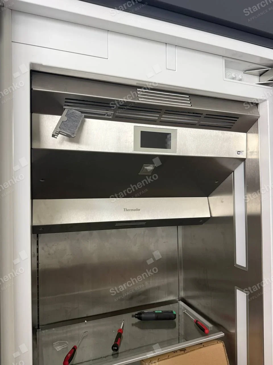 Thermador built-in column refrigerator with the air filter holder pulled out of the upper vent and service tools on the shelf
