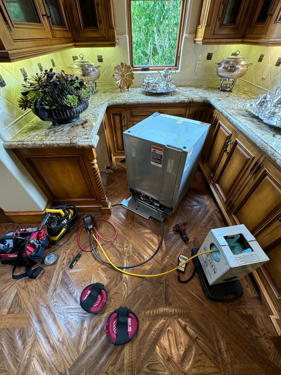 Under-counter wine fridge removed from its cabinet with pressure gauges beside it