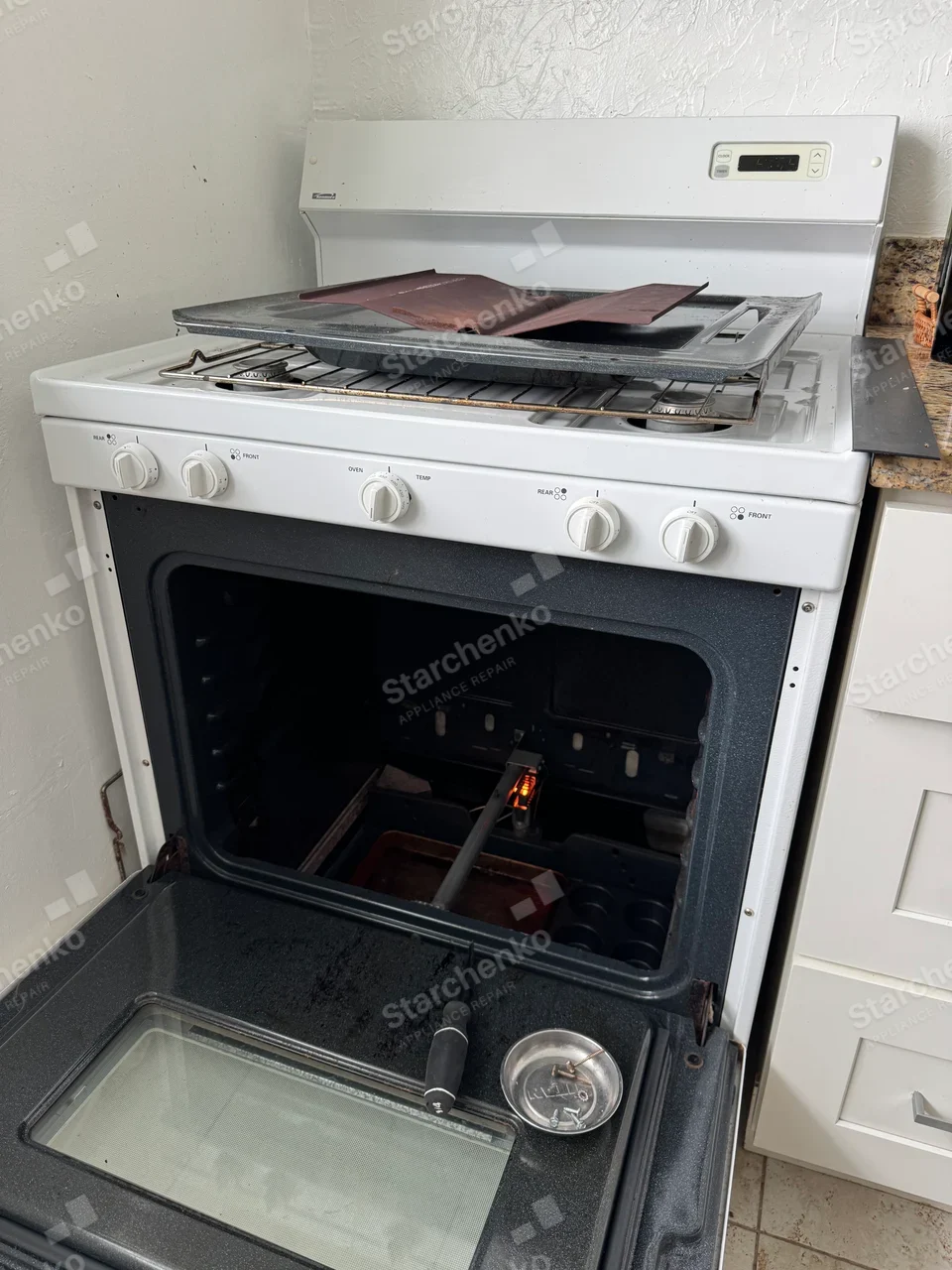 Kenmore gas range with the oven door open and the bake burner igniter glowing inside
