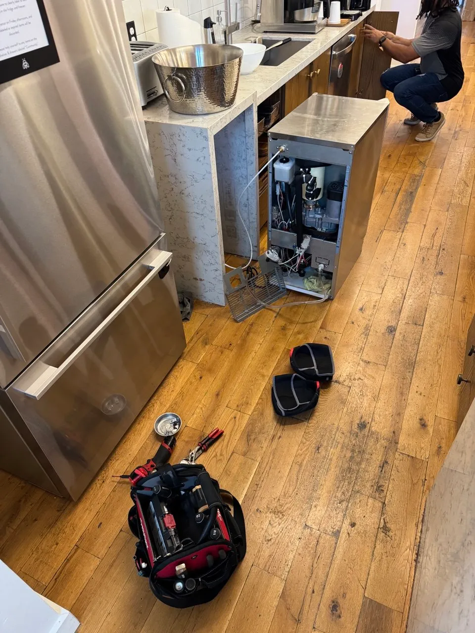Stainless under-counter wine cooler pulled onto the floor beside a tool bag